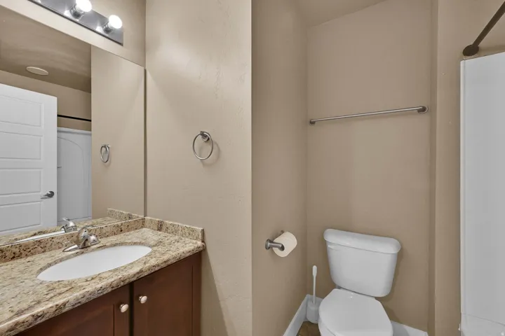 Vanity with a granite countertop, undermount sink, and wood-finish cabinetry