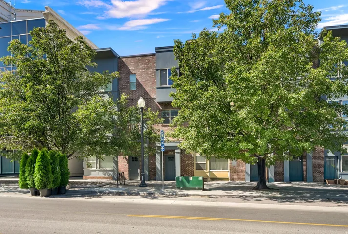 Mid-row Townhome with brick exterior and a tree lined street