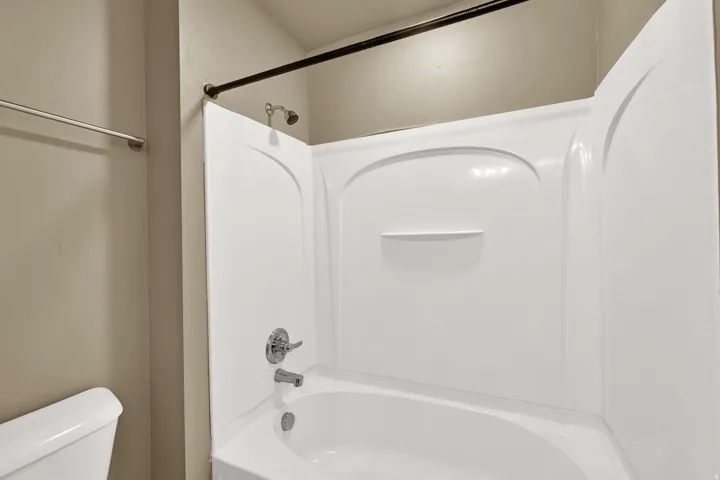 White bath/shower combination with integrated shelving and chrome fixtures