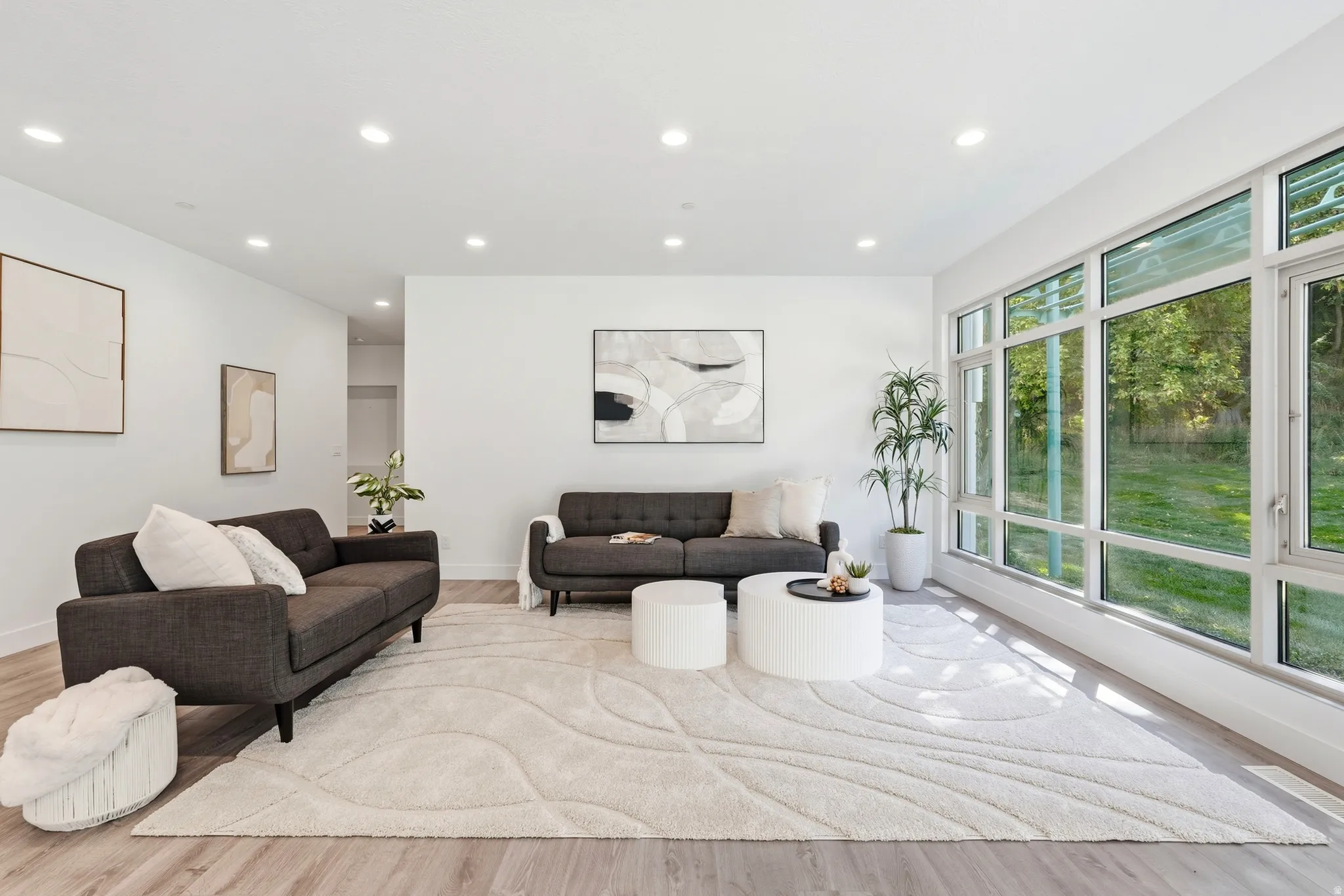 Recessed ceiling lighting, wood-finish flooring, expansive window wall, and white wall finishes