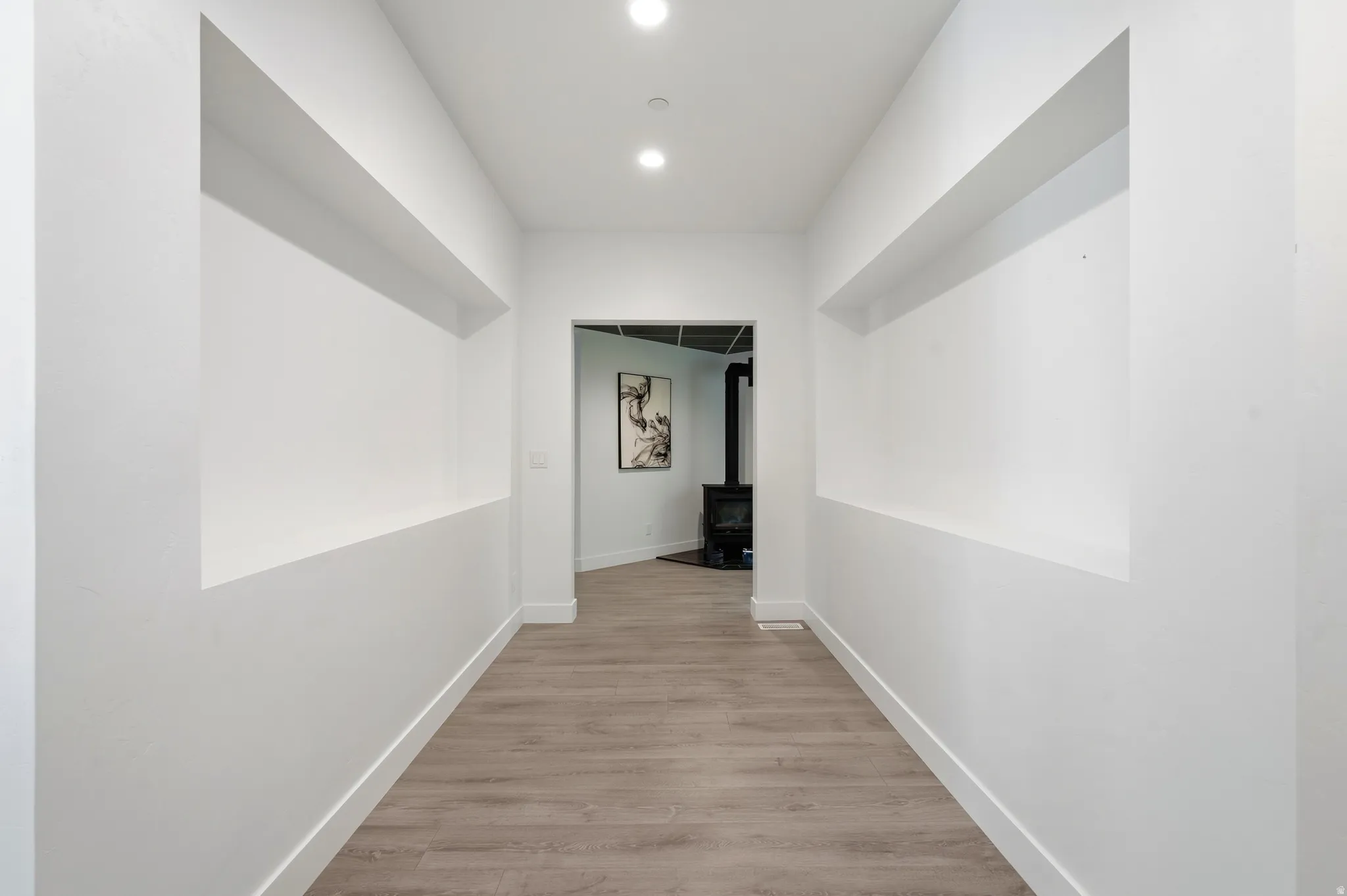 Hallway with recessed wall niches, wood-finish flooring, and recessed lighting