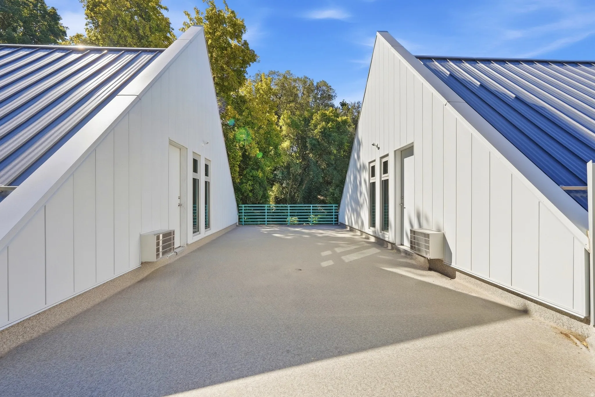 Expansive outdoor deck featuring a textured surface, surrounded by distinct architectural structures with metal roofs and vertical siding