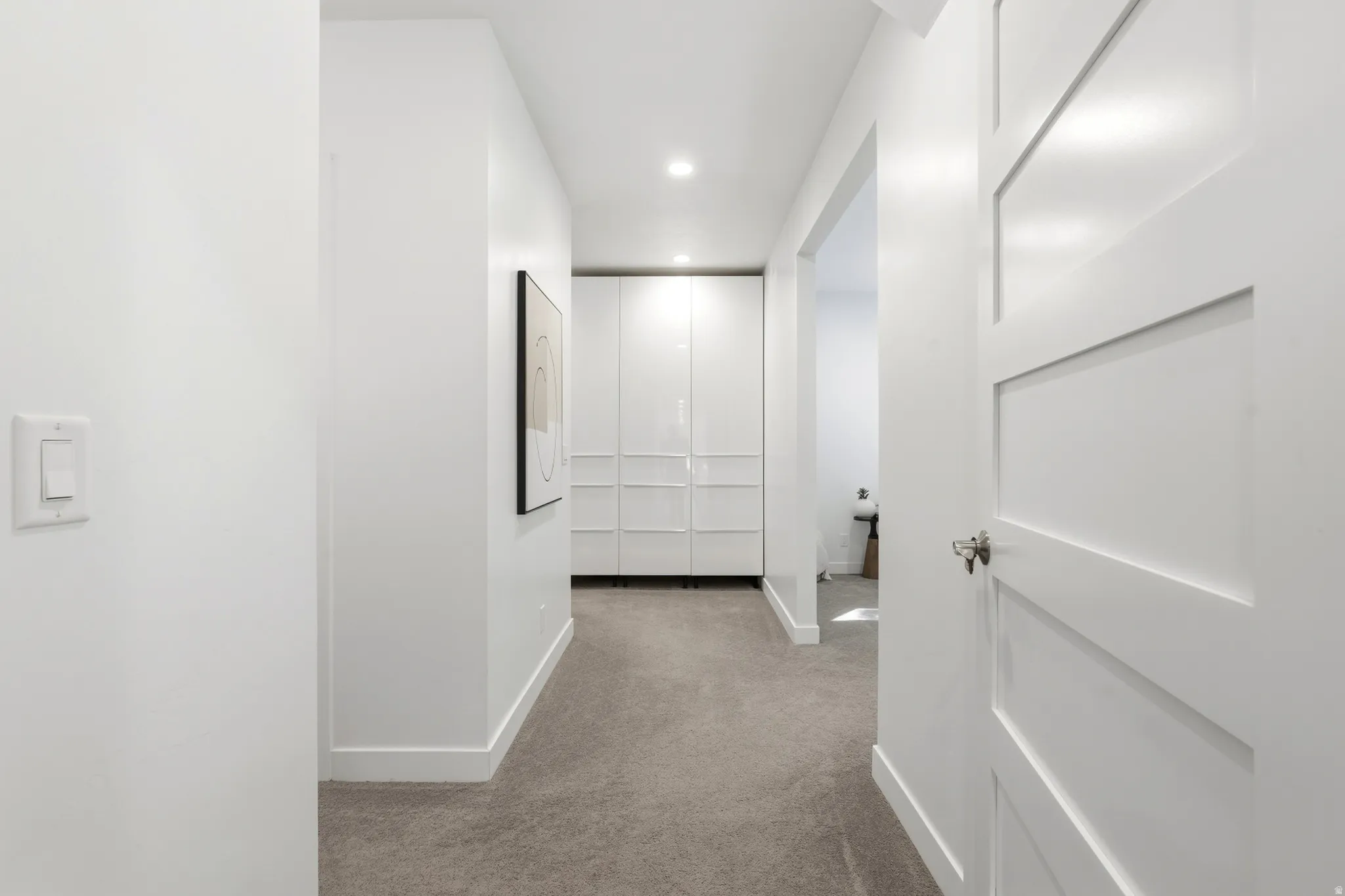 Hallway featuring recessed lighting, a paneled door, gray carpet, and white built-in cabinetry