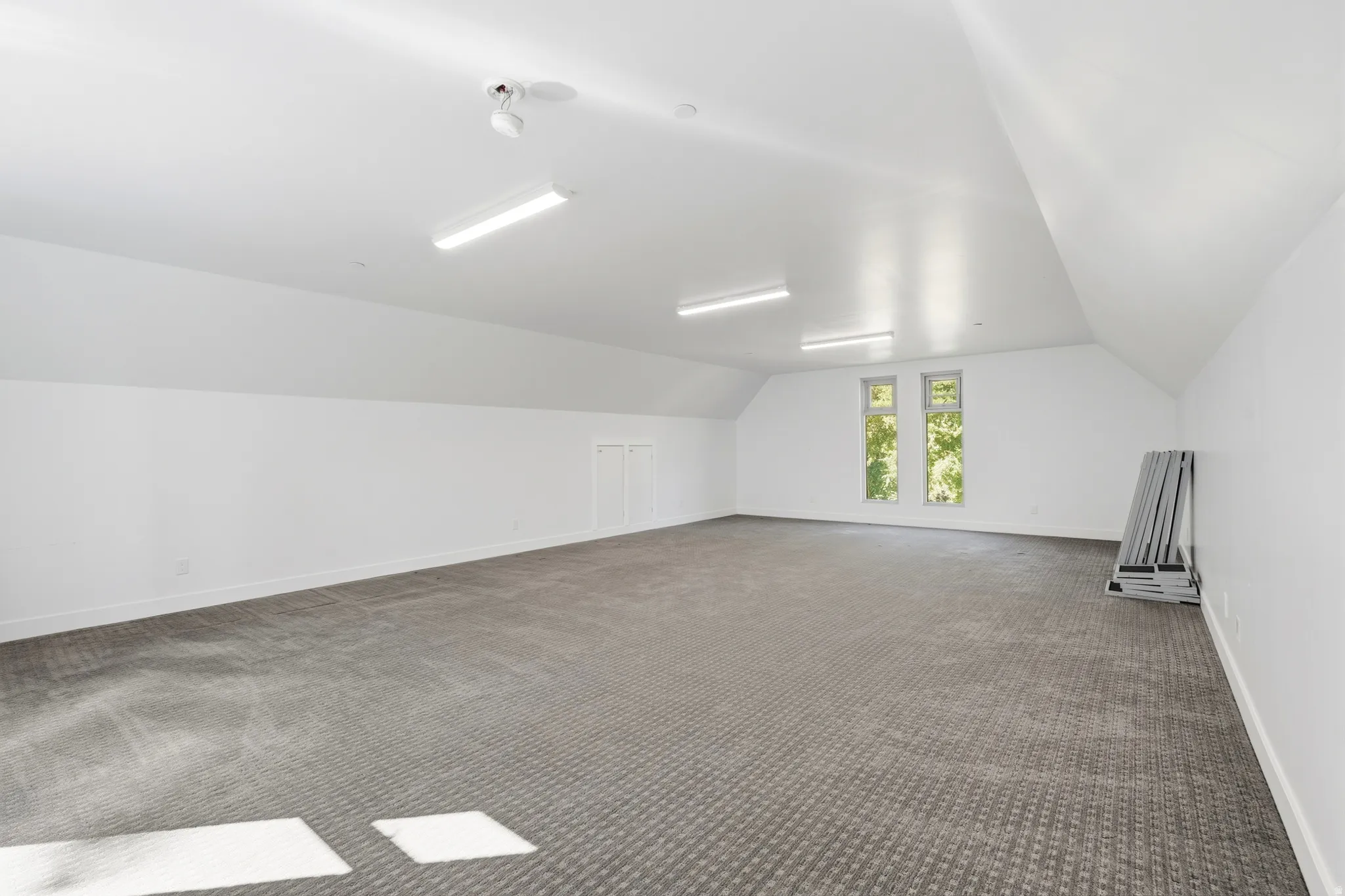 Expansive room with vaulted ceilings, recessed lighting, and two windows
