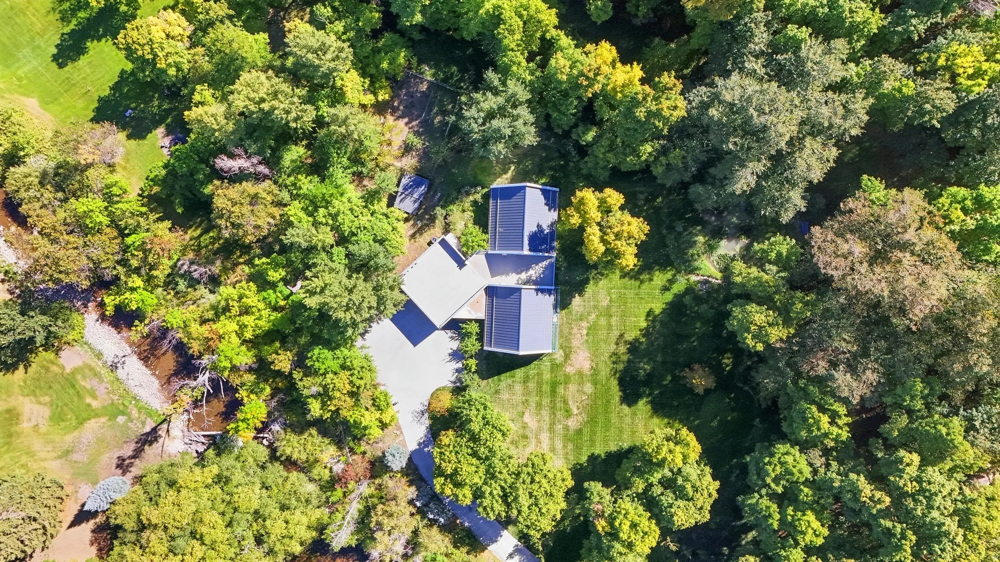 Expansive grounds with mature trees, manicured lawns, and a private stream