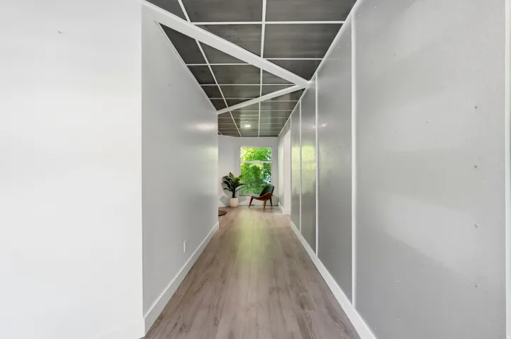 Wood-finish flooring with a grid-patterned ceiling, light-toned walls, and a large window