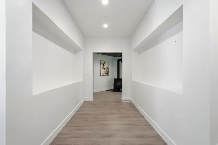 Hallway with recessed wall niches, wood-finish flooring, and recessed lighting