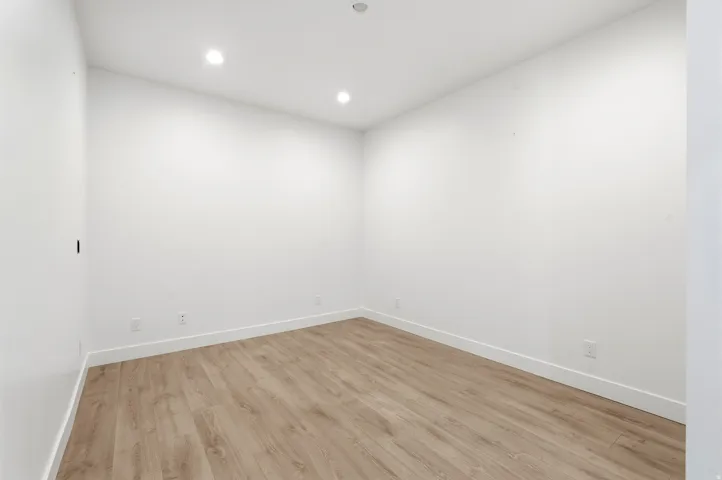 Recessed ceiling lighting, wood-finish flooring, and white walls