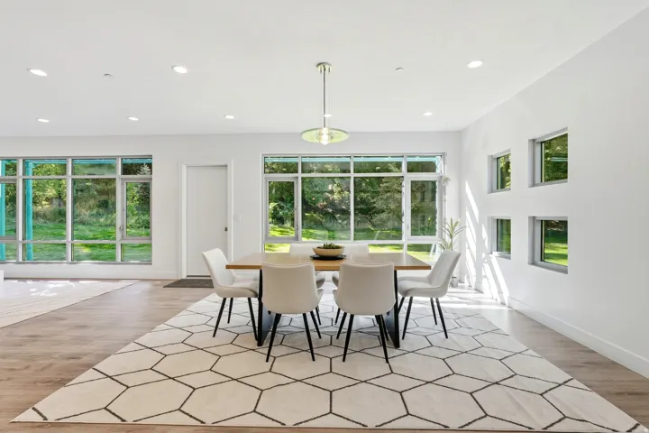 Recessed lighting throughout, wood-finish flooring, a modern pendant light fixture, and multiple large windows with exterior scenery