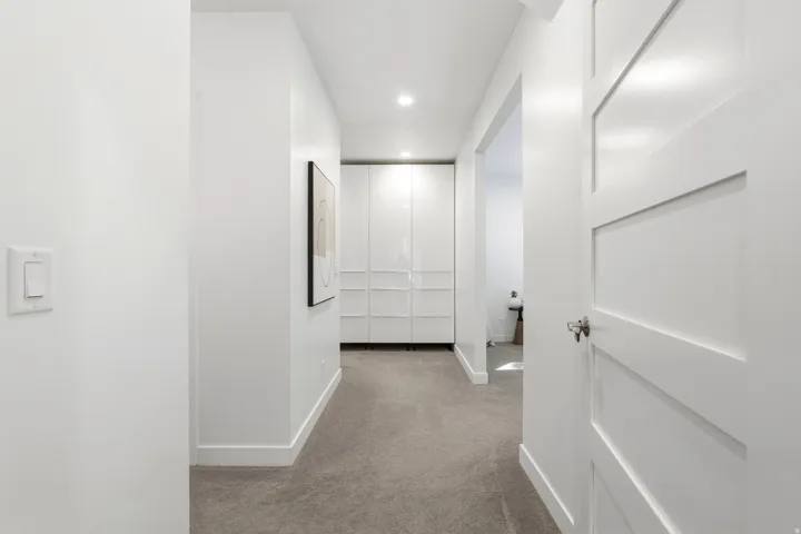 Hallway featuring recessed lighting, a paneled door, gray carpet, and white built-in cabinetry