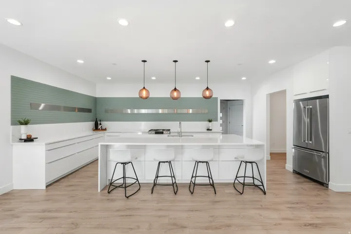 Modern kitchen featuring a large center island with seating, white flat-panel cabinetry, stainless steel appliances, and wood-finish flooring
