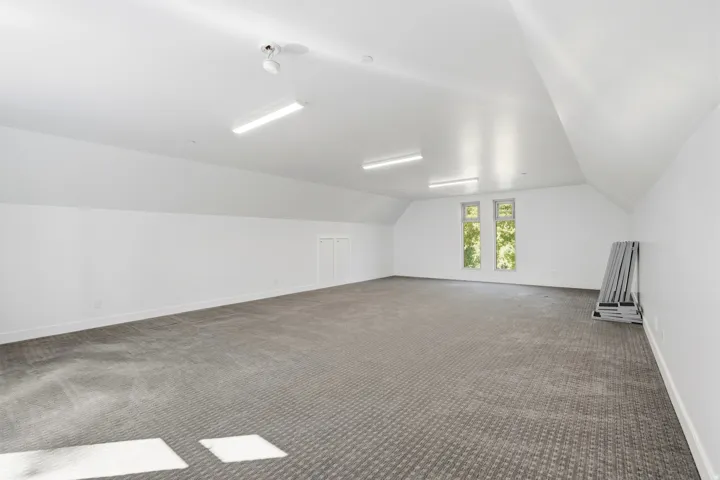 Expansive room with vaulted ceilings, recessed lighting, and two windows