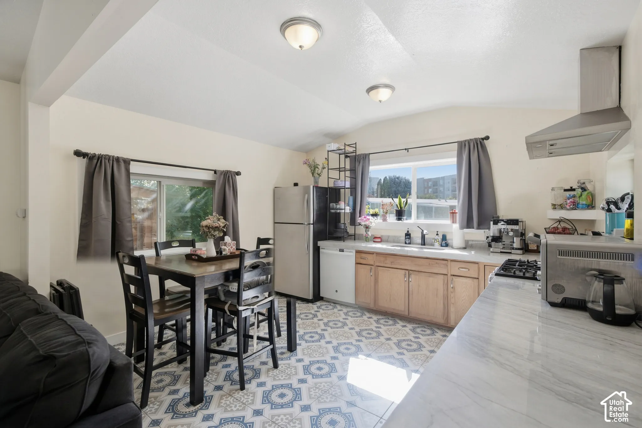 Kitchen with patterned tile flooring, light wood-finish cabinetry, and a stainless steel refrigerator