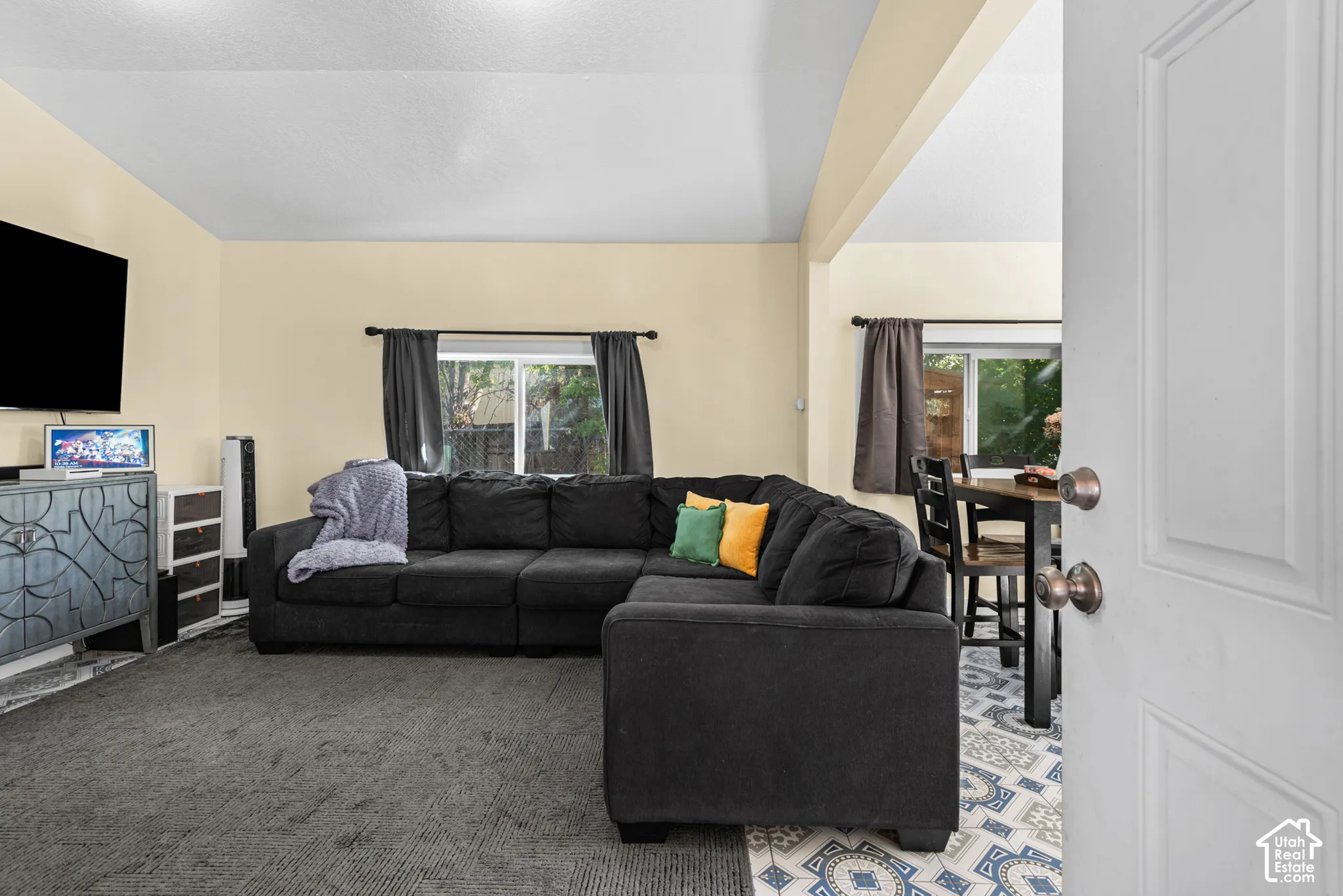 Open concept living area with light-colored walls and carpet flooring