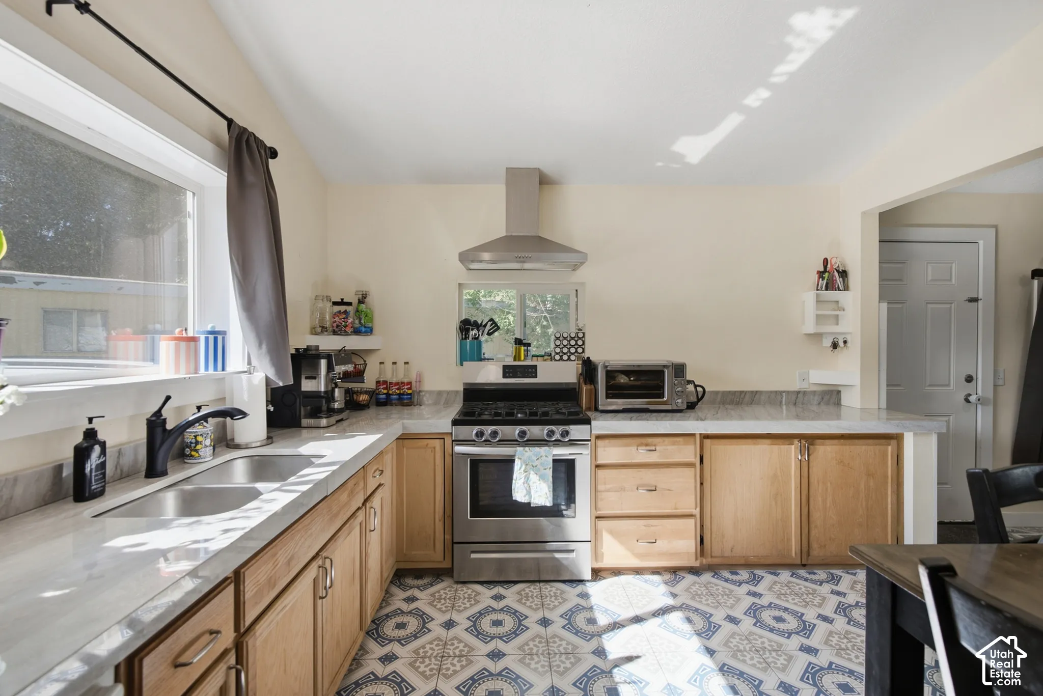 Range hood that vents outside, gas stove, tile flooring and large kitchen window