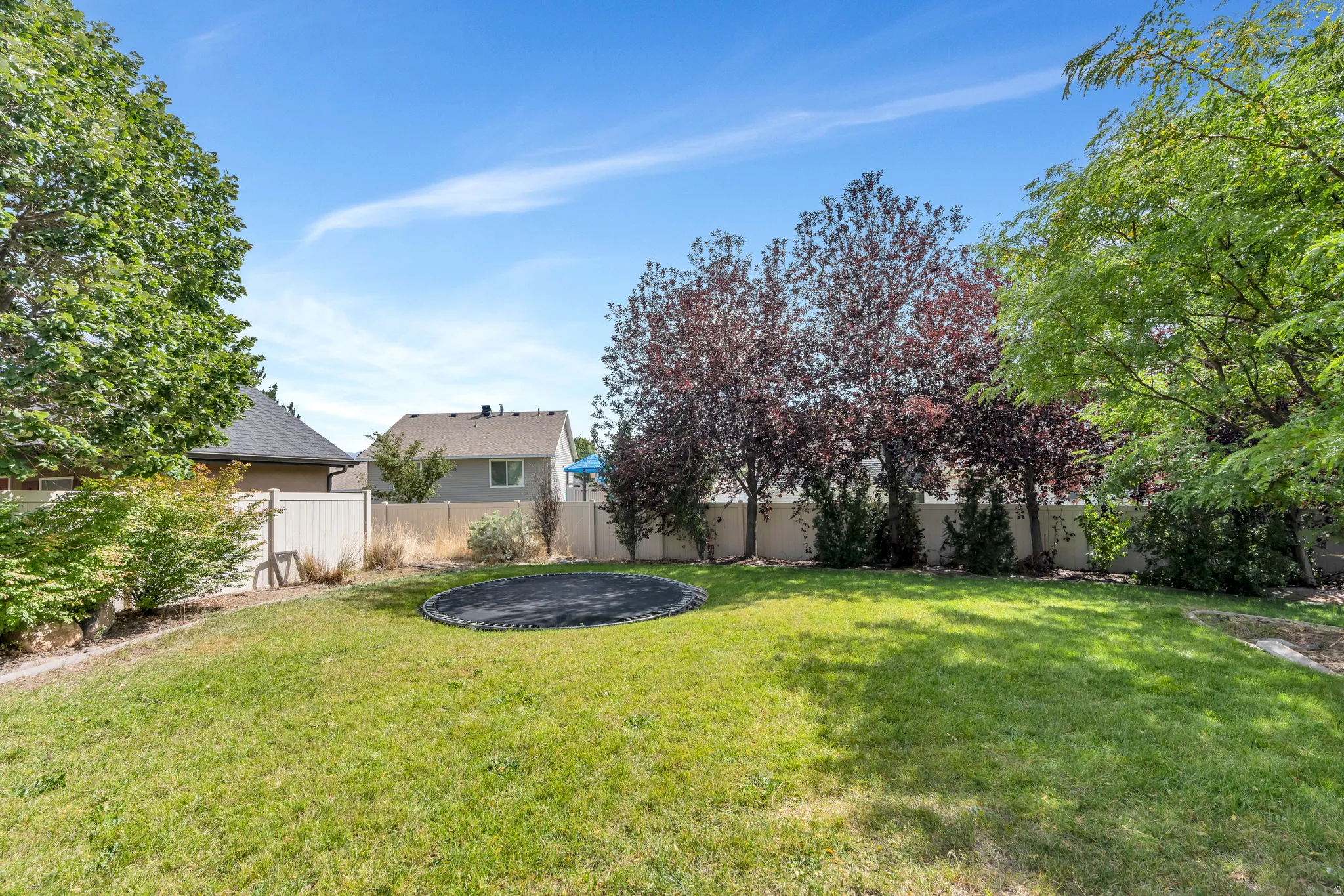 Expansive lawn area with mature trees and perimeter fencing