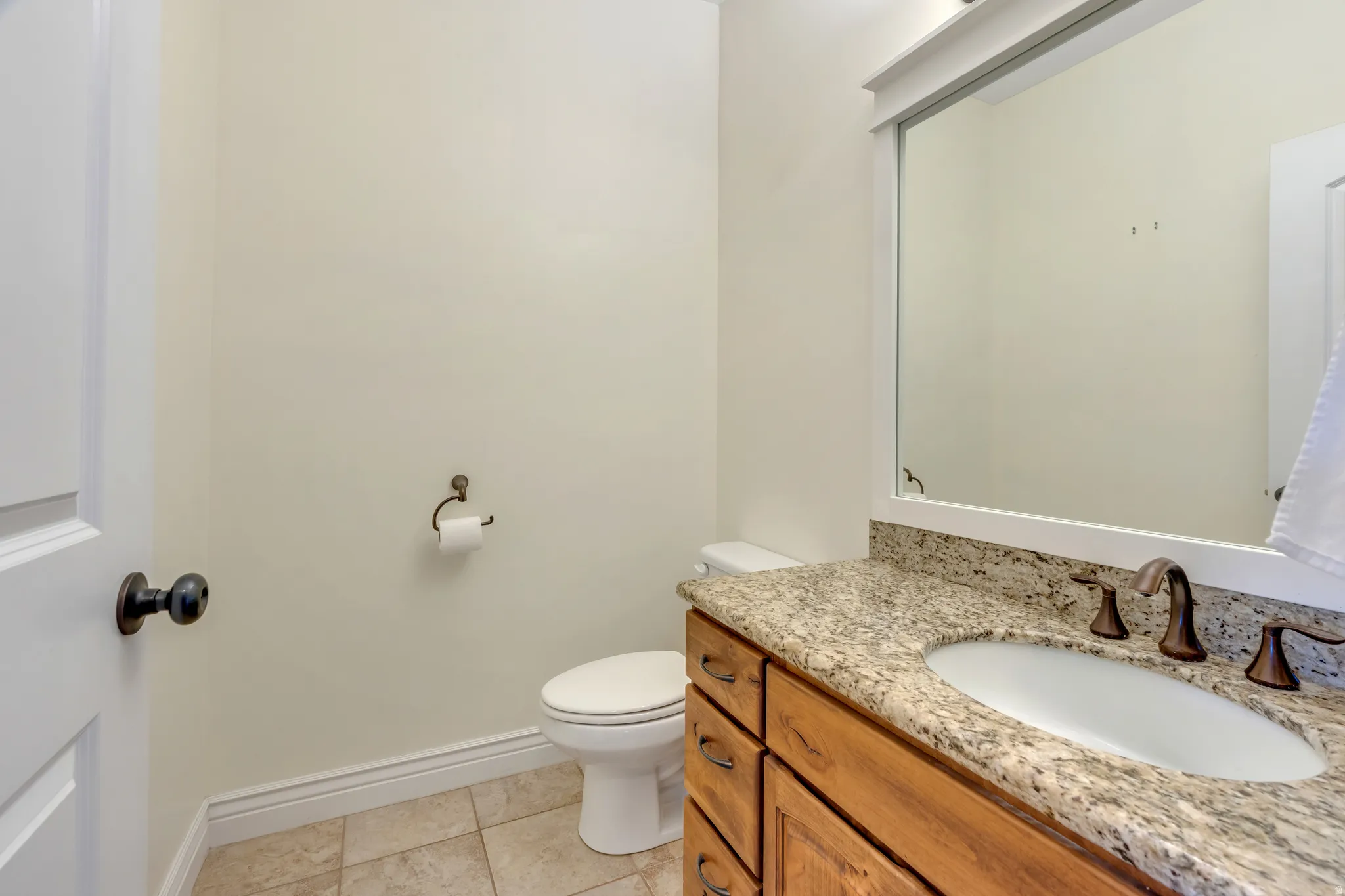Vanity with a granite countertop, undermount sink, and bronze-finish fixtures