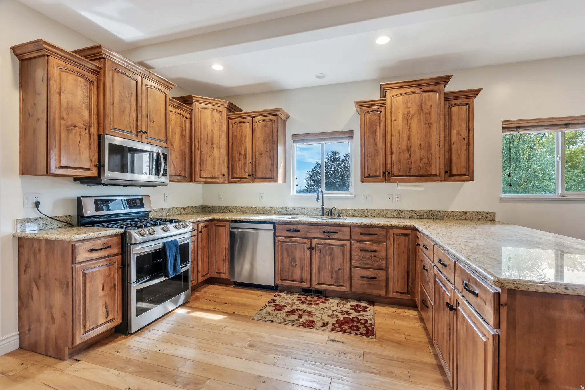U-shaped kitchen featuring wood-finish cabinetry, light-toned countertops, and stainless steel appliances