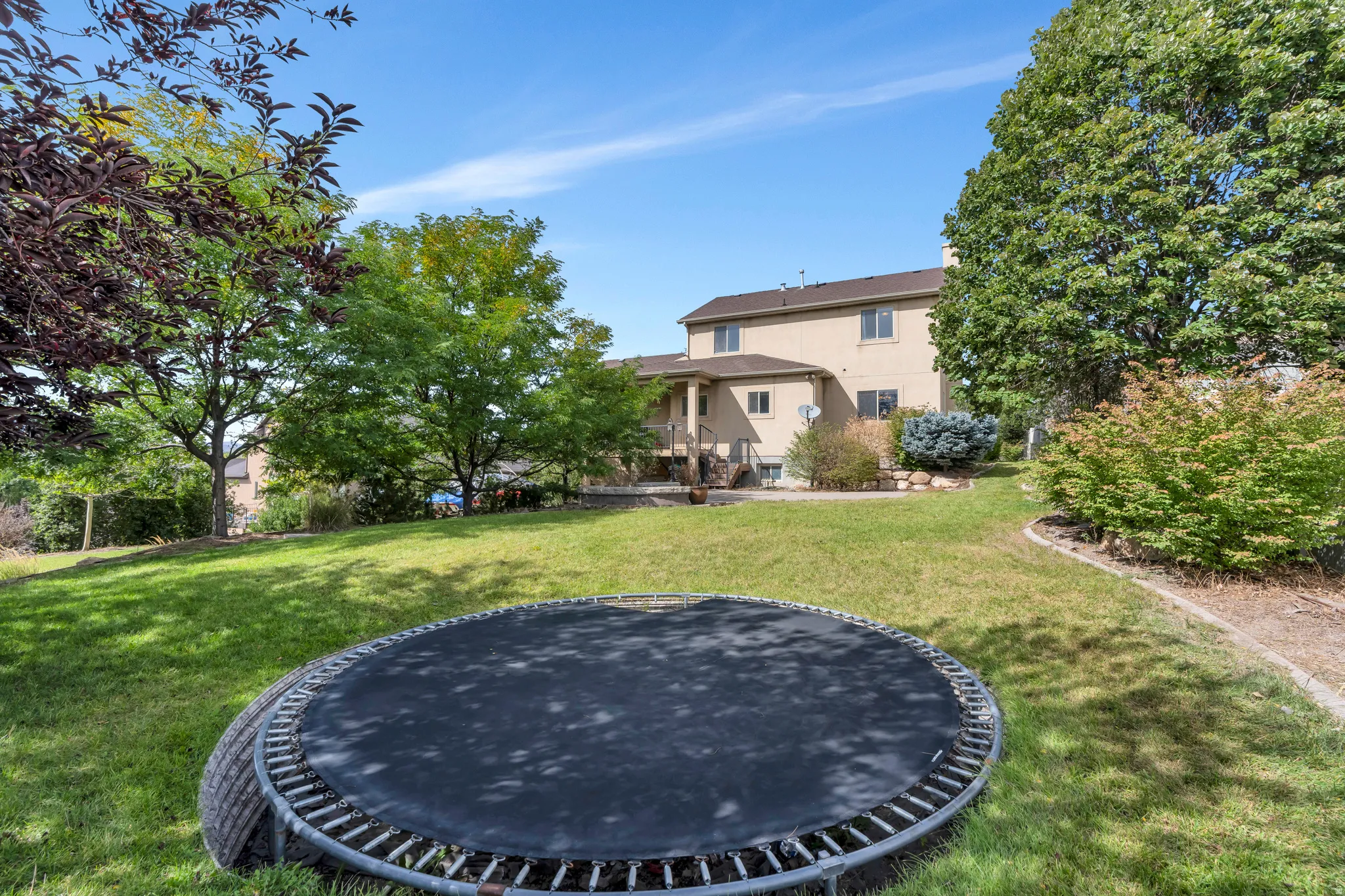 Expansive terraced yard with mature trees, established landscaping, and a multi-level exterior