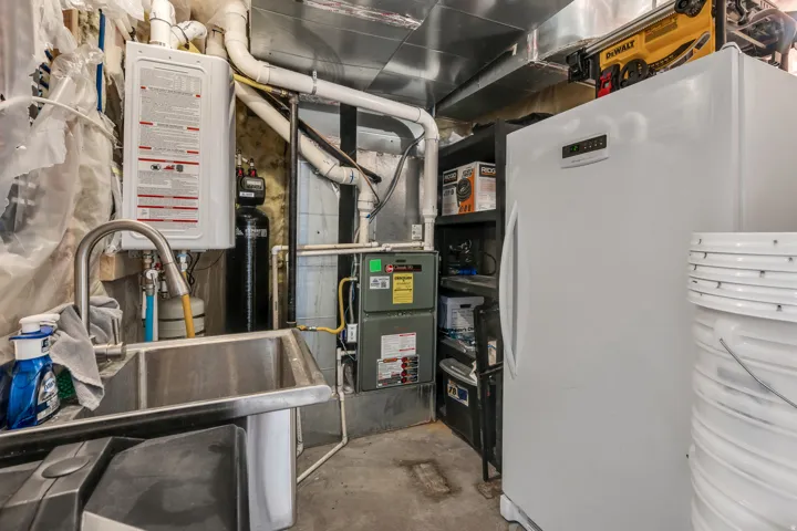 Utility sink with gooseneck faucet, wall-mounted water heater, and a water filtration system