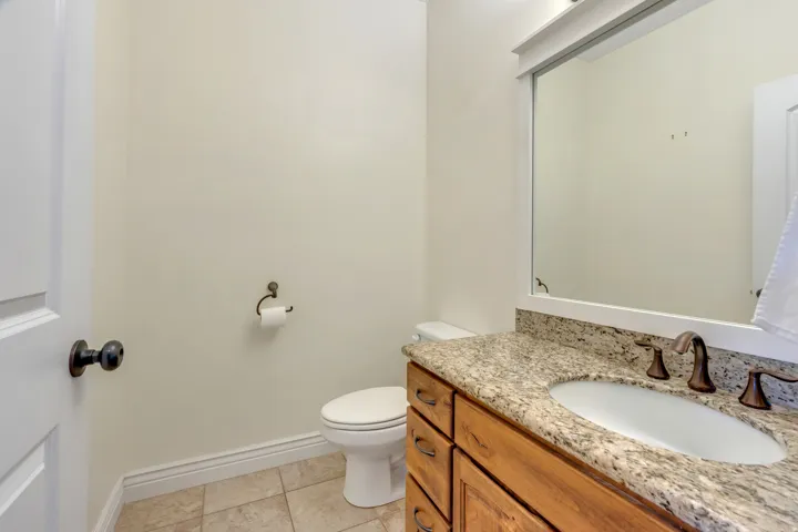 Vanity with a granite countertop, undermount sink, and bronze-finish fixtures