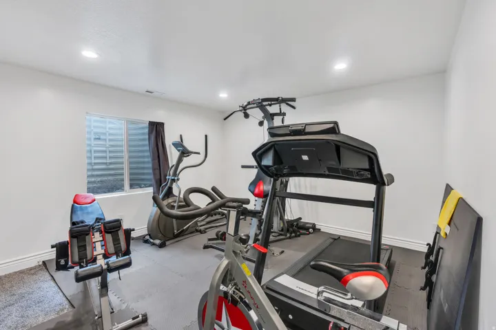 Recessed lighting illuminates a versatile space featuring a window with privacy covering and rubber flooring