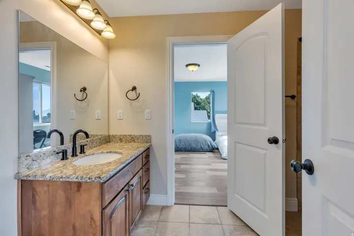 Wood-finish vanity with a light granite-patterned countertop and an undermount sink