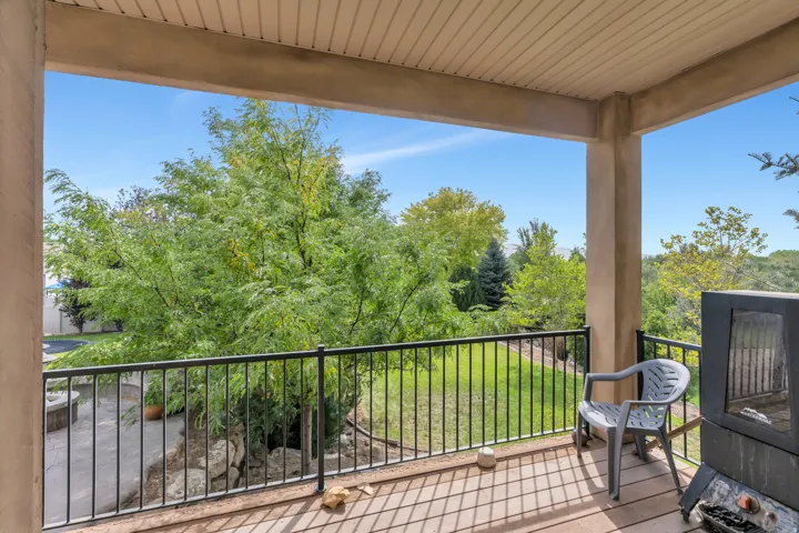 Covered balcony featuring a black metal railing, composite wood-finish decking, and a built-in outdoor fireplace