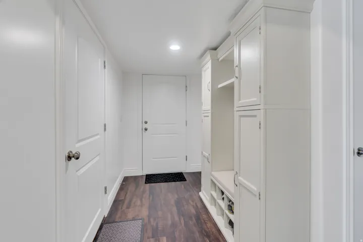 Hallway with wood-finish flooring, recessed lighting, and white built-in cabinetry featuring shelving and a bench