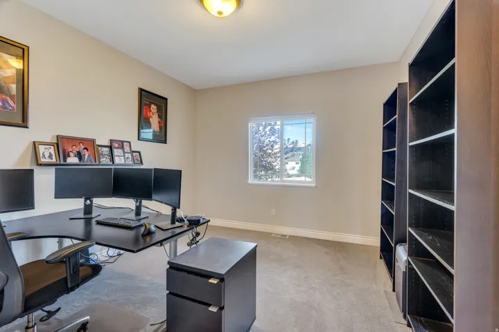Carpeted flooring, single pane window, wall-mounted shelf, built-in shelving units, and a ceiling-mounted light fixture
