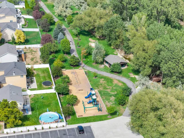 Neighborhood park with a children's playground, a paved walking path, and mature trees