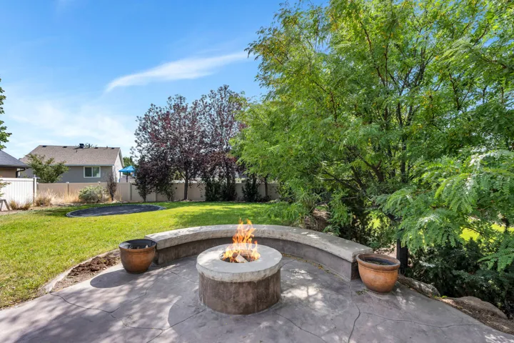 Stamped concrete patio with a built-in fire pit, curved seating, and mature trees