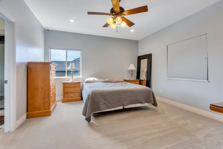 Carpeted bedroom with a ceiling fan, recessed lighting, and a window