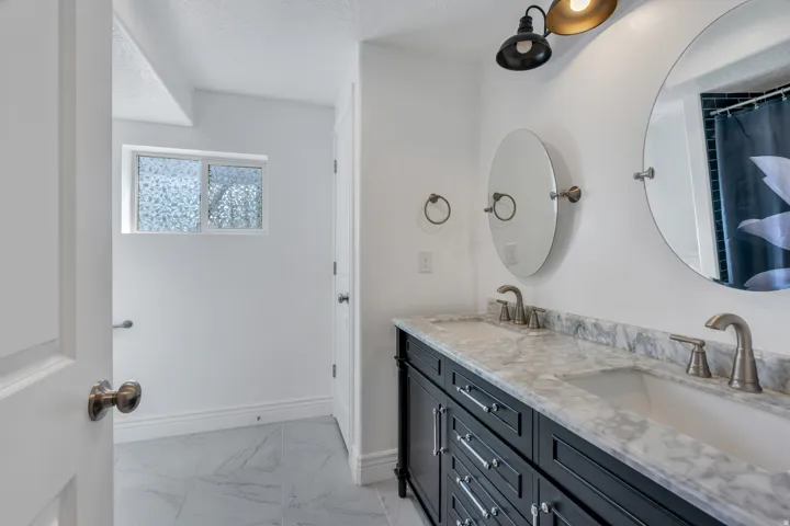 Double vanity with stone countertop, dual undermount sinks, and satin nickel fixtures