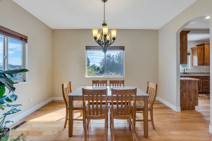 Bright dining space featuring wood-finish flooring, two windows, and an arched entryway