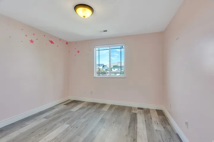 Light wood-finish flooring, white trim, and a window with a white frame
