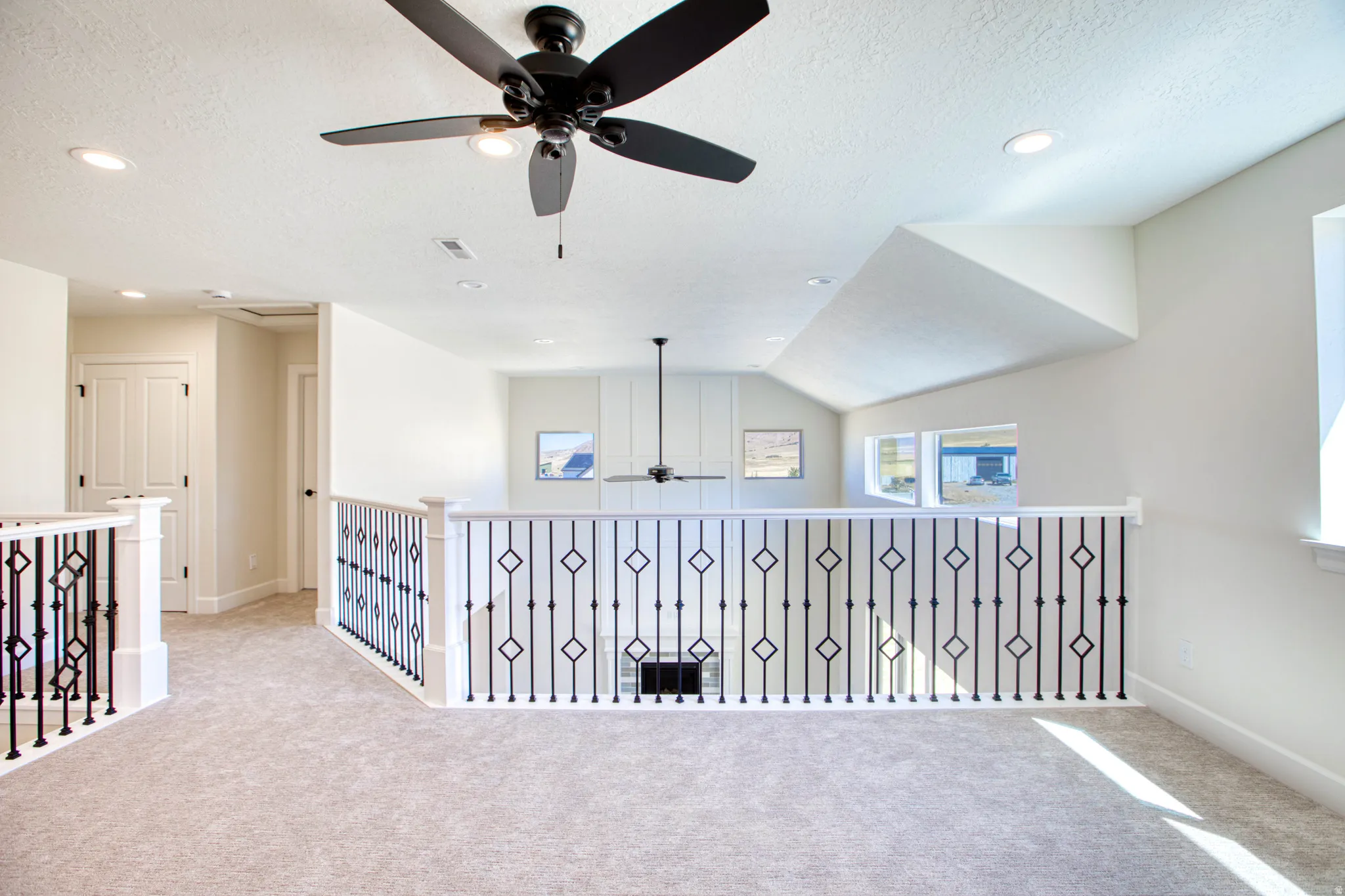 Upper-level landing featuring textured carpeting, white painted walls, recessed lighting, and a contemporary ceiling fan