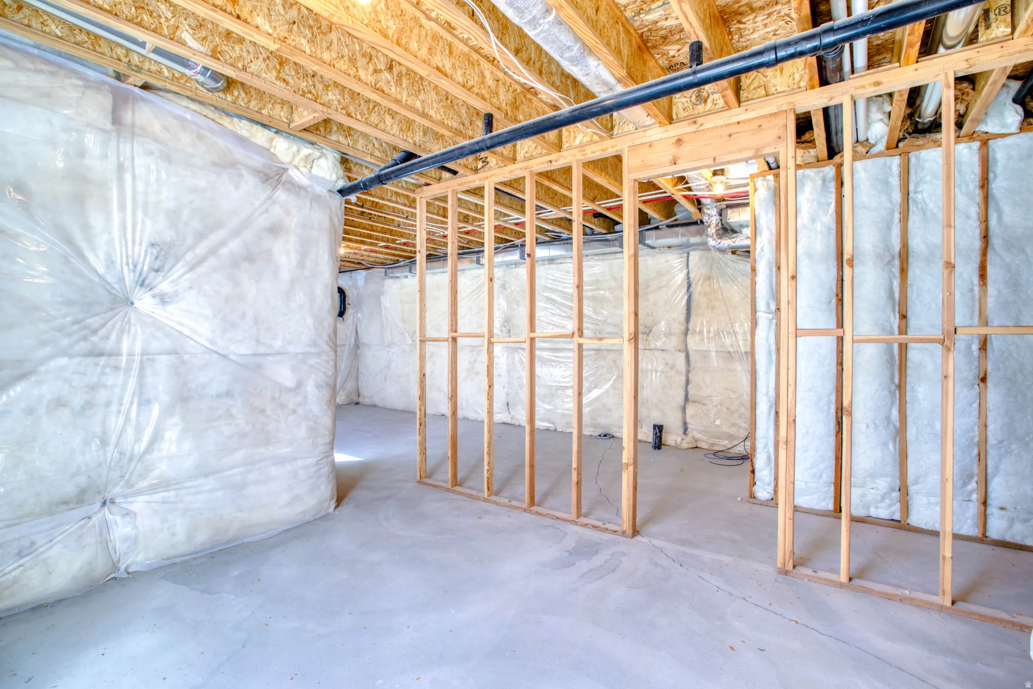Unfinished basement with concrete flooring, wood framing, and exposed ceiling joists