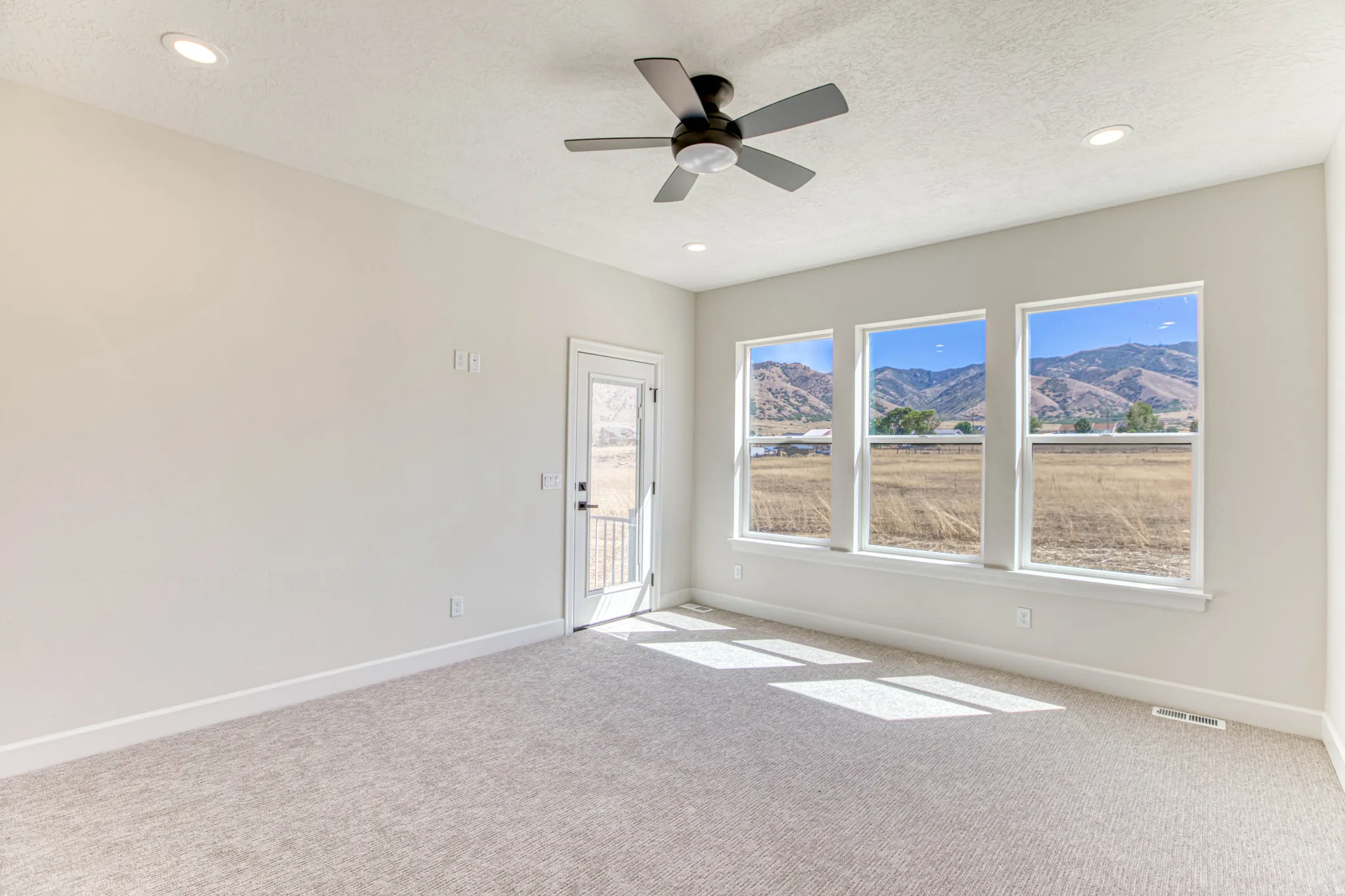 Recessed lighting, ceiling fan, three large windows, direct outdoor access, and mountain scenery