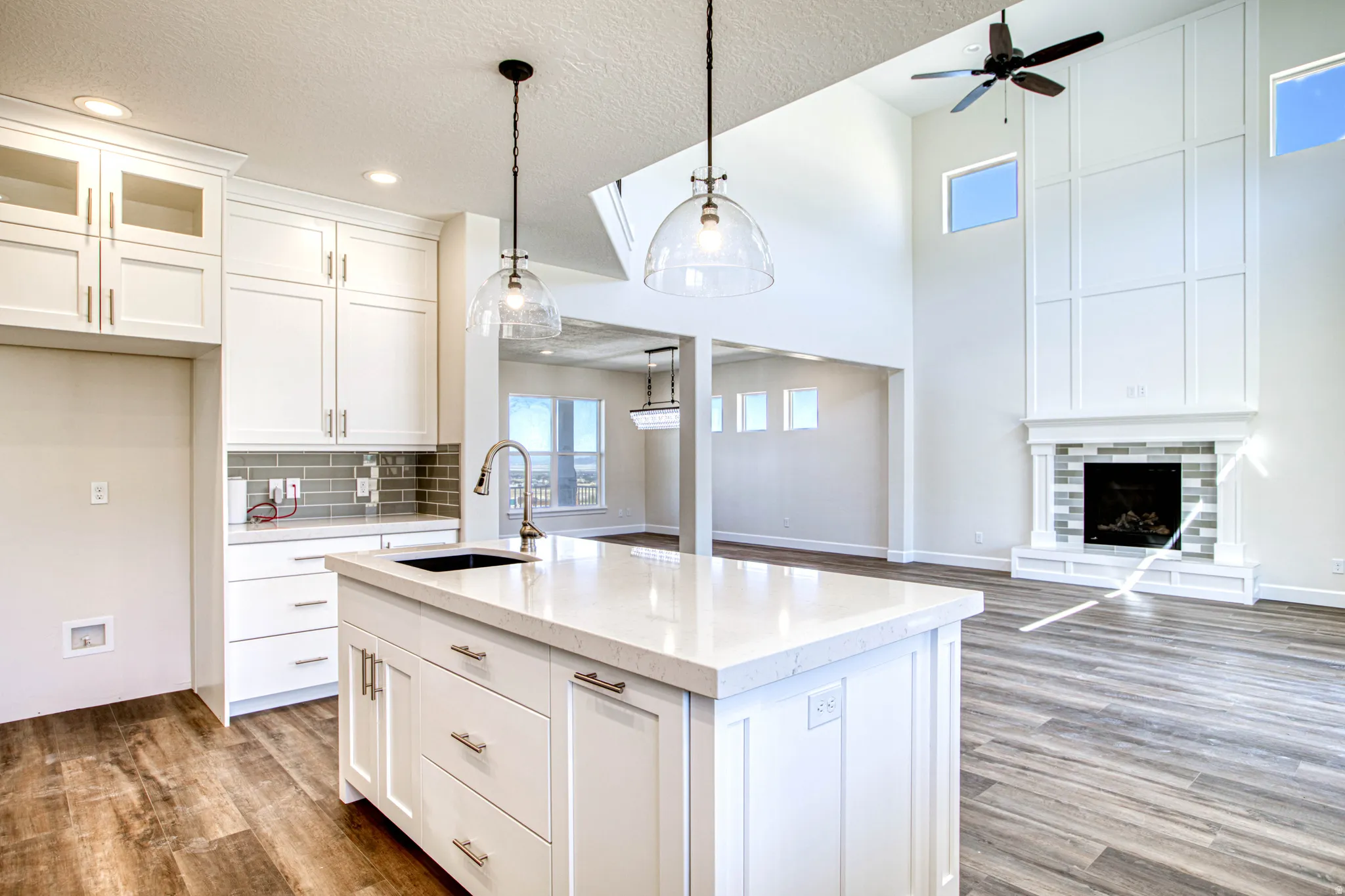 Kitchen island with integrated sink, white cabinetry, and pendant lighting