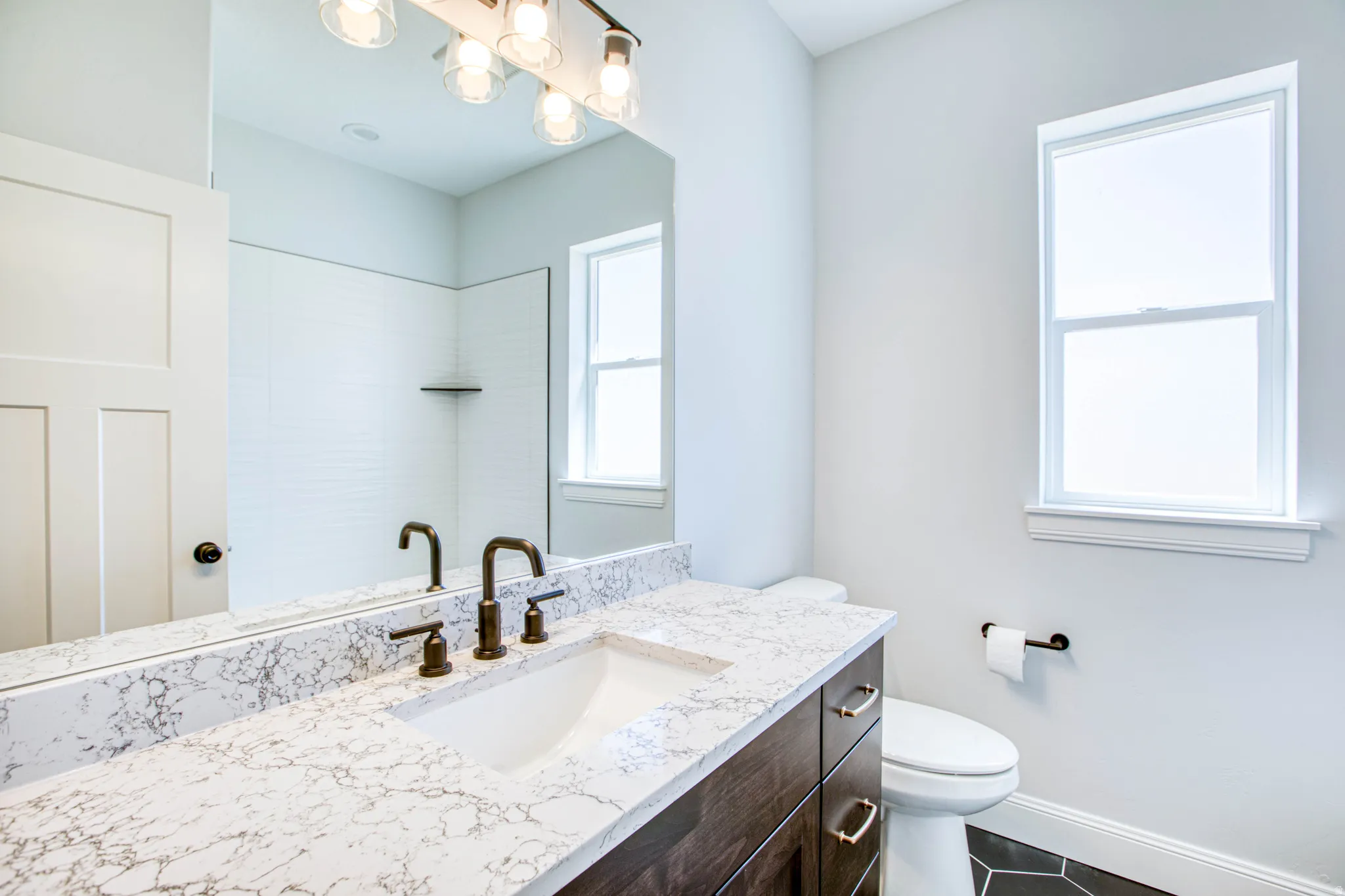 Vanity with a white countertop and integrated sink, bronze-finish faucet, and coordinating hardware