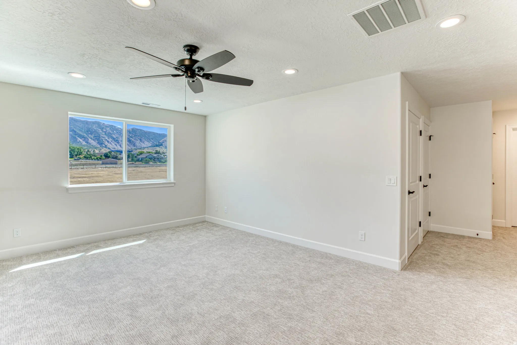 Expansive room featuring light-toned carpeting, recessed lighting, and a contemporary ceiling fan