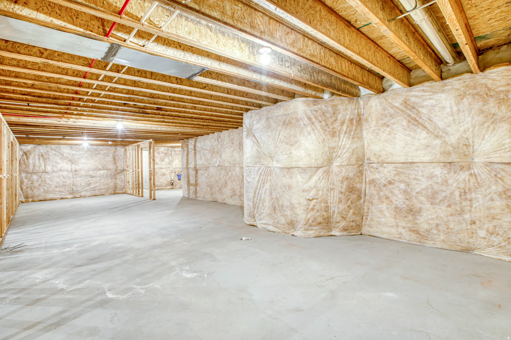 Unfinished basement featuring exposed wood joists and concrete flooring