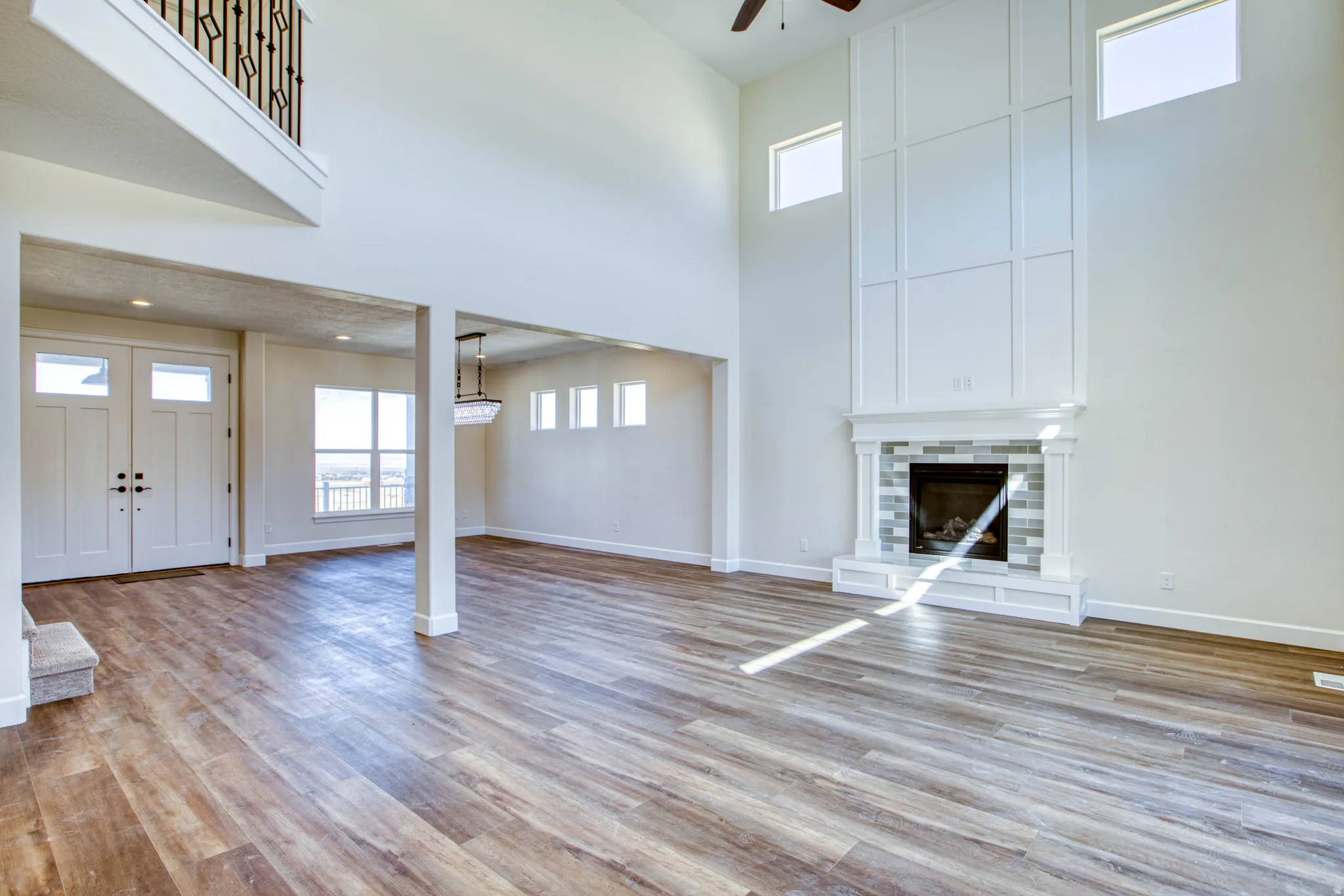 Two-story living area with wood-finish flooring, a contemporary fireplace with tile surround, and a ceiling fan