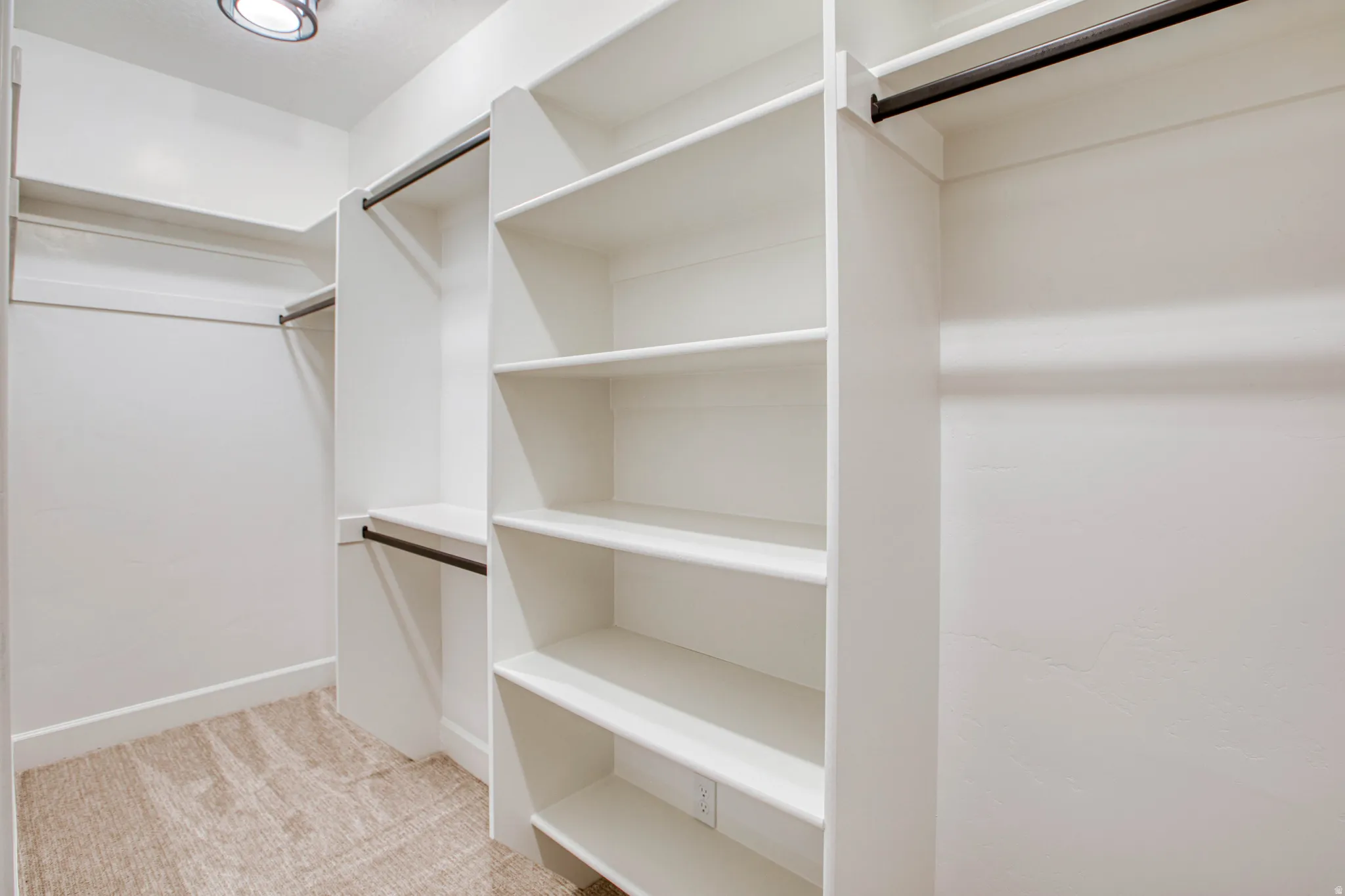 Built-in shelving, multiple hanging rods, recessed ceiling light, and carpet flooring