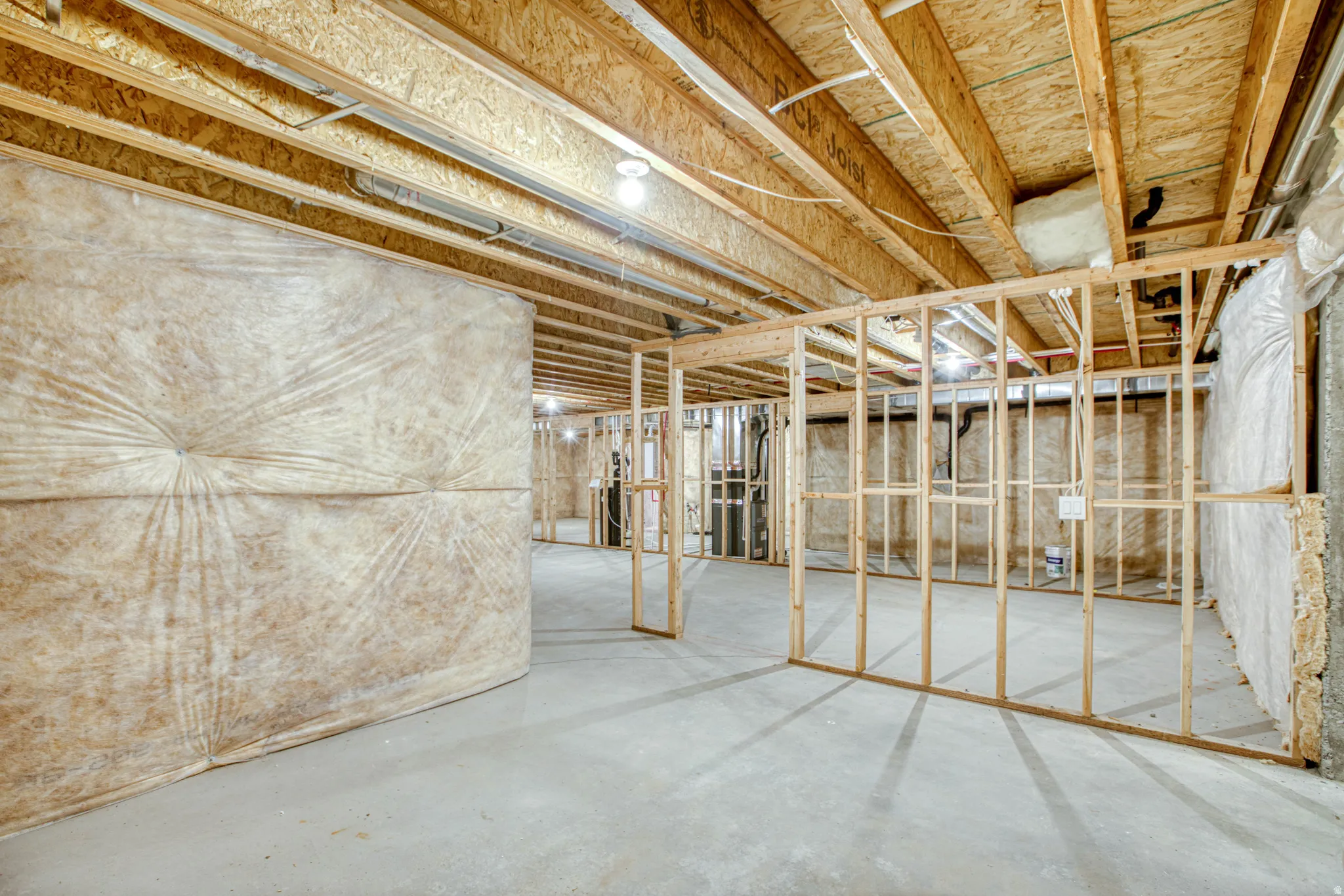 Unfinished basement with exposed ceiling joists, concrete flooring, and partial wall framing