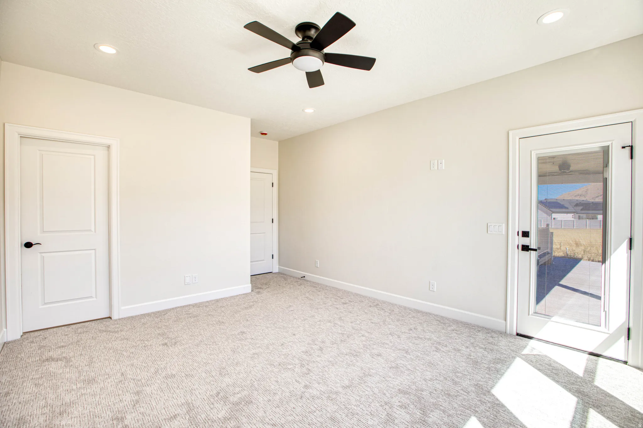 Recessed lighting, ceiling fan with integrated lighting, neutral-toned carpet flooring, white paneled doors, and a glass-paneled exterior door