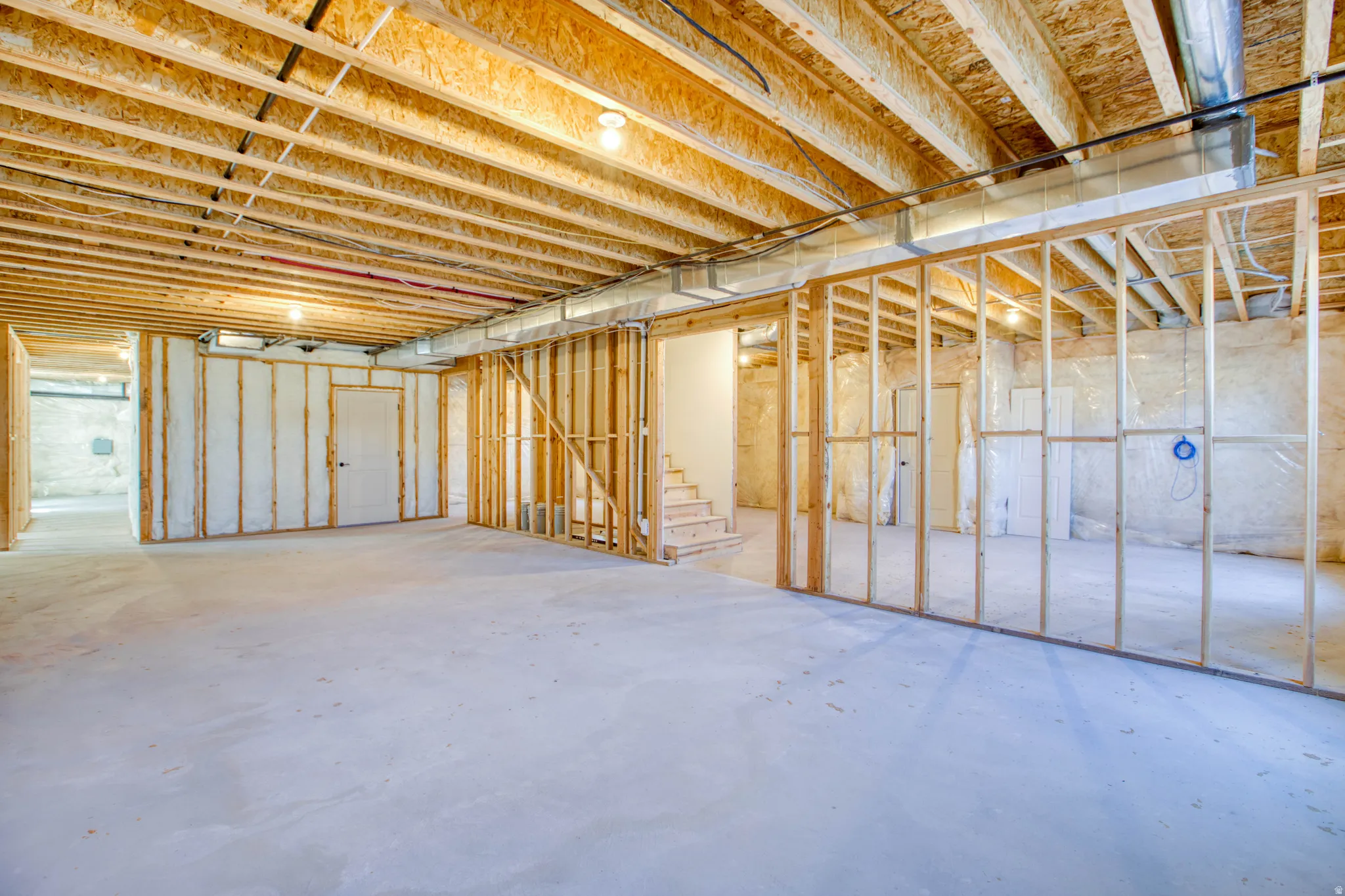 Unfinished basement with exposed wood framing, concrete flooring, and visible ductwork