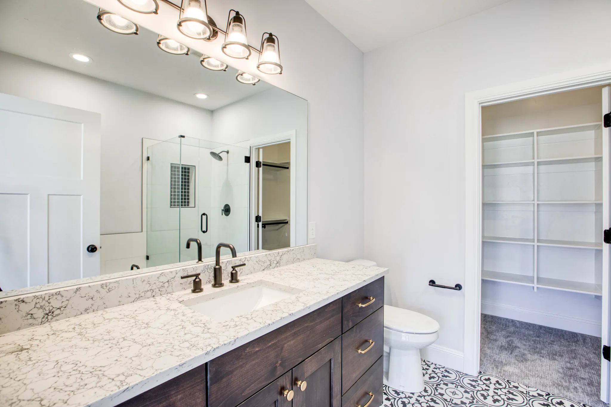 Dark wood-finish vanity with gold-tone hardware, rectangular undermount sink, and light-toned countertop
