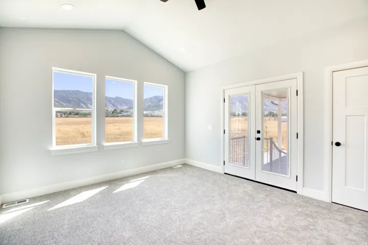Vaulted ceiling, recessed lighting, three large windows, double glass panel doors, and neutral carpet